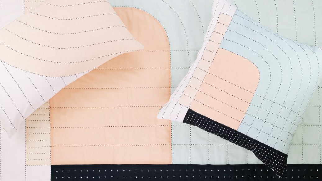 Two Curve Throw Pillows on top of Seema Curve Quilt Throw from Anchal's Curve Series