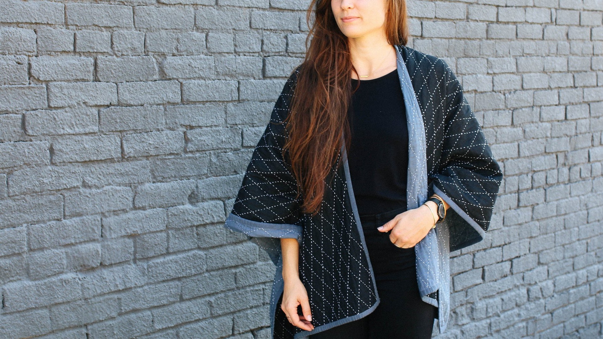 Shawl from Anchal's Narrative collection being modeled in front of a black brick wall