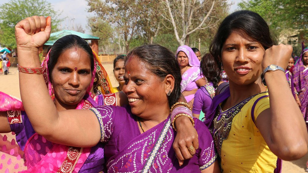 Three artisans with their arms around each other holding up fists as a sign of empowerment