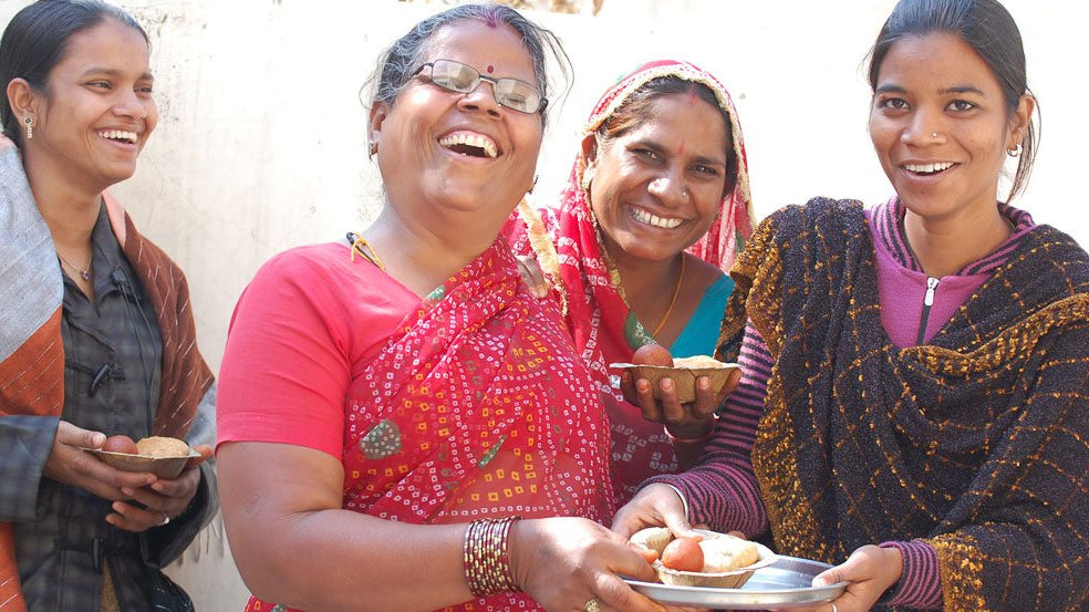 alt="Four Indian women gathered, laughing and smiling joyfully"