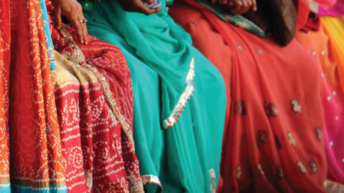 Close up photo of traditional saris in colors of red teal and orange