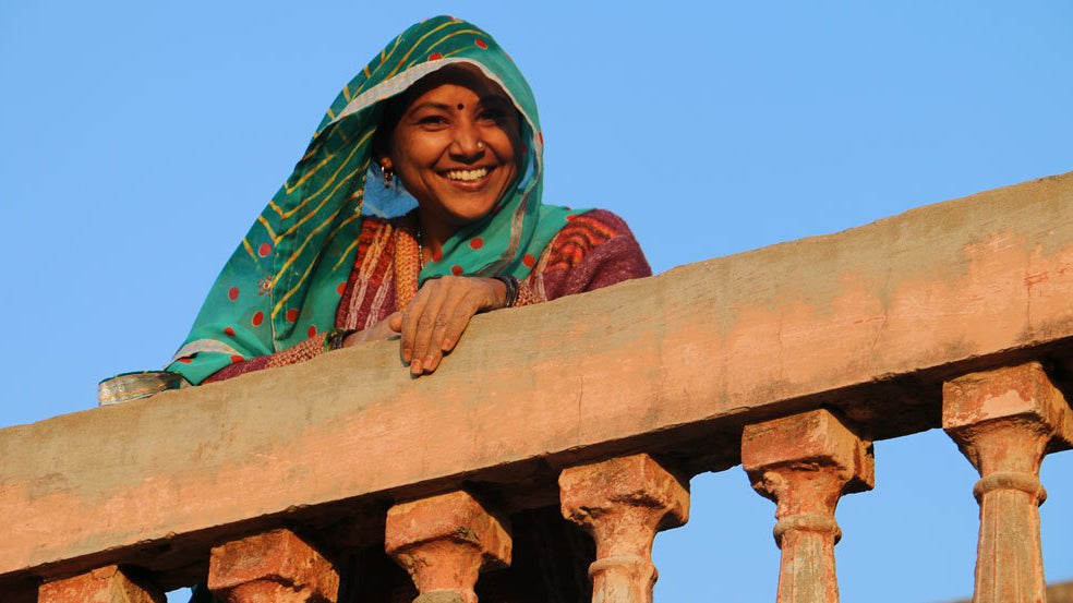 Young artisan woman leaning and smiling over a balcony