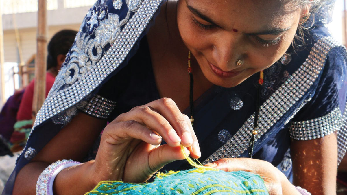 Anchal artisan sewing an intricate pattern into a teal fabric