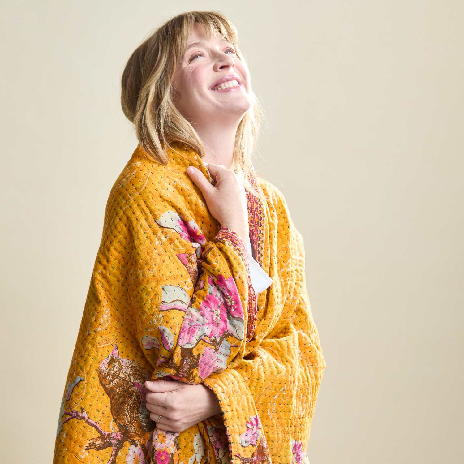 woman wrapped in an orange kantha quilt