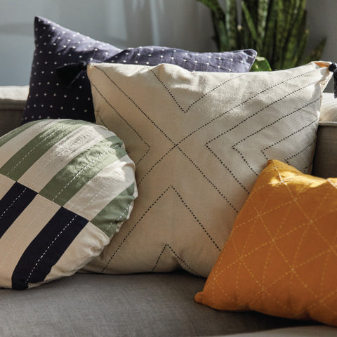 colorful organic cotton throw pillows on gray sofa hand-embroidered in India by Anchal artisans