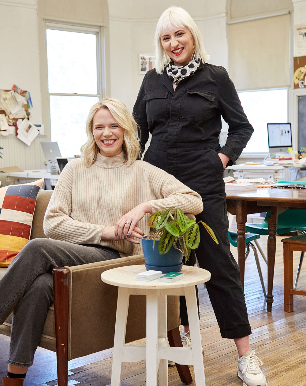 Two women in a casual office setting with a plant on a small table, Maggie and Colleen Clines in Louisville, KY
