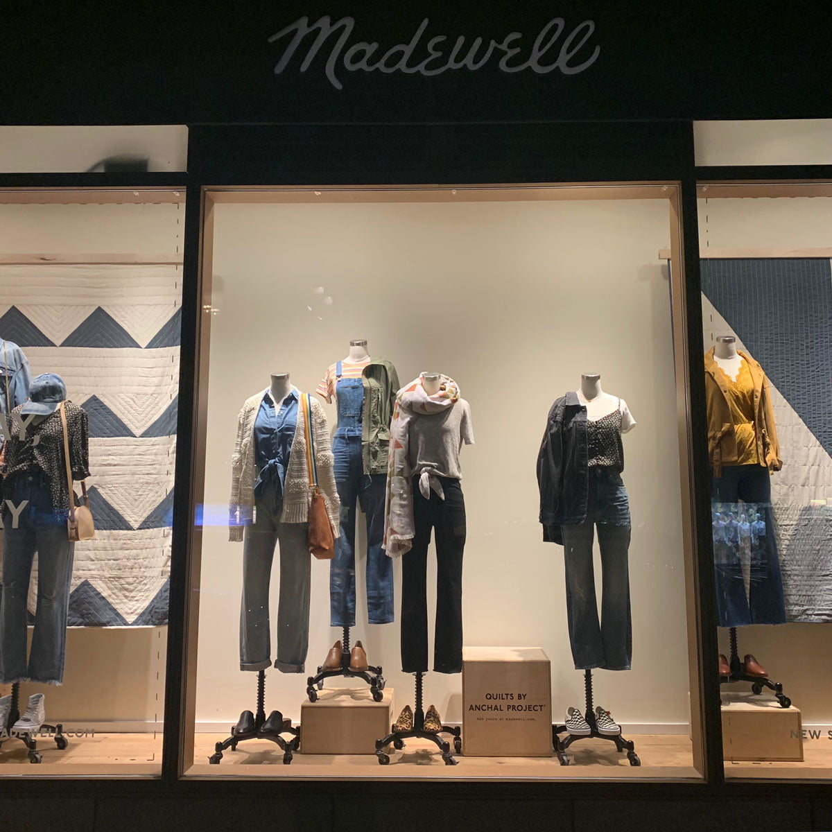 Madewell x Anchal, photo of Madewell storefront window featuring Anchal's triangle patchwork quilt hanging in the background