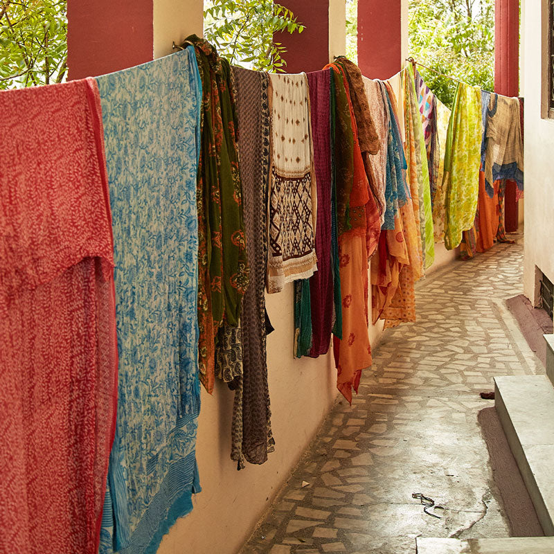 Colorful vintage cotton saris hanging on a line against a building wall