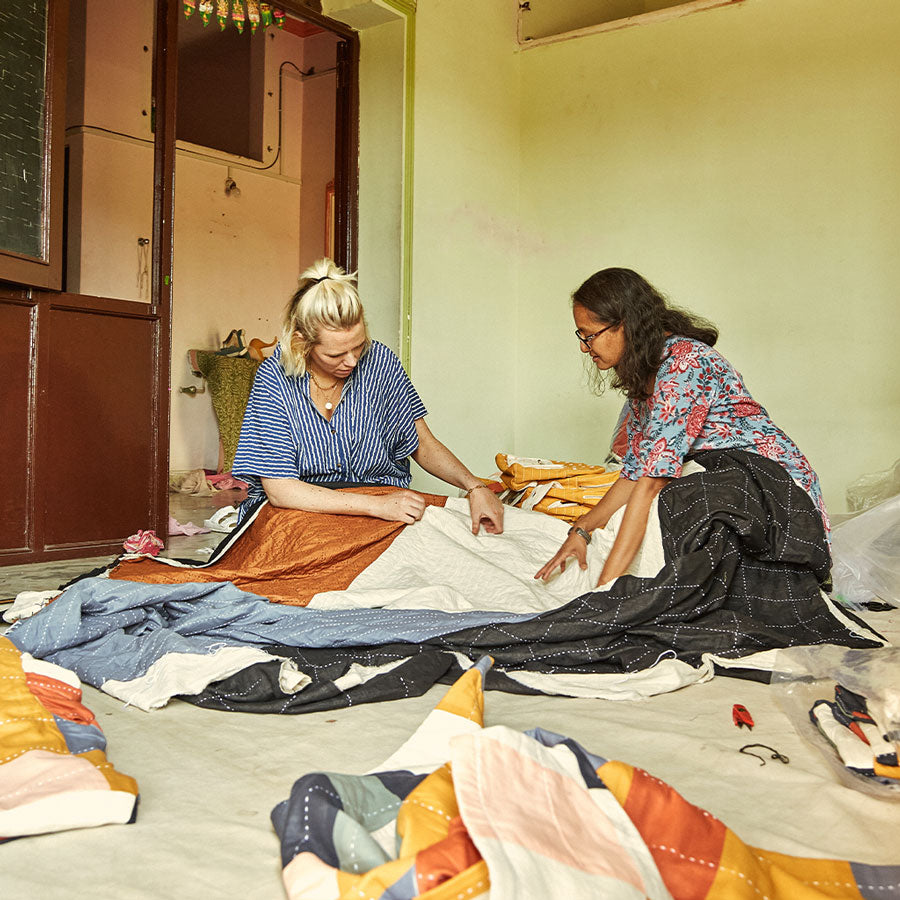 women looking at a modern kantha quilt in a studio in India