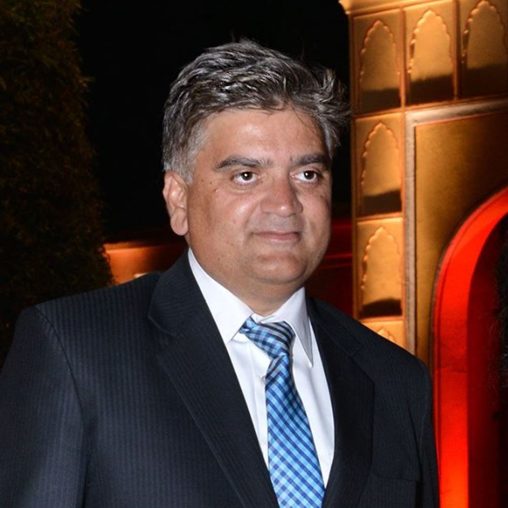 Man in a suit with a blue tie standing in front of a decorative wall, Hitesh, NGO Founder