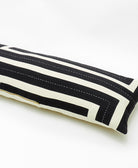 Black and white striped pillow with a gold zipper on a white background