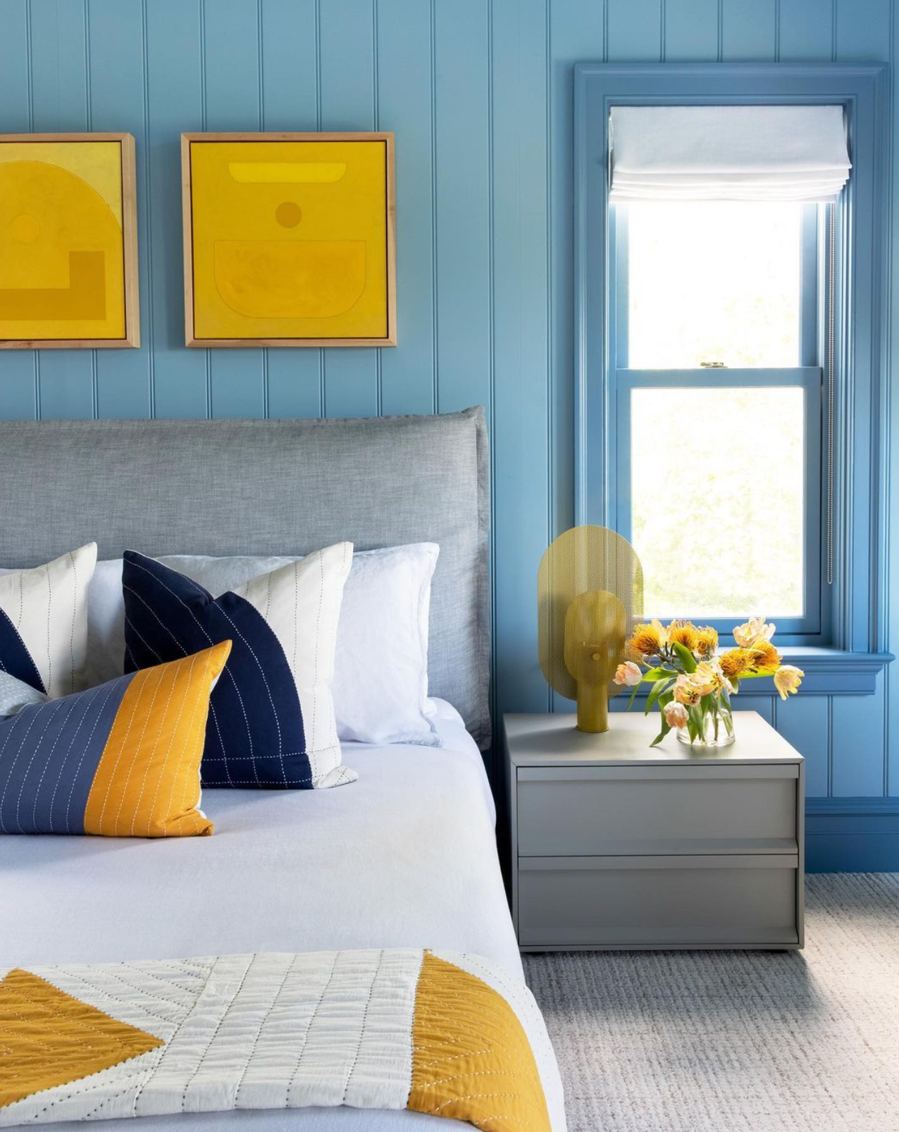 blue and yellow themed bedroom with mustard yellow and navy blue throw pillows on all white bed