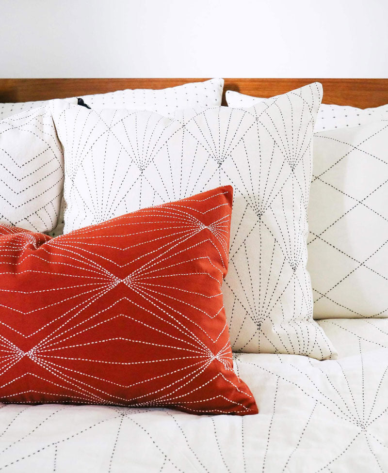 Red and white patterned pillows on a bed with a wooden headboard
