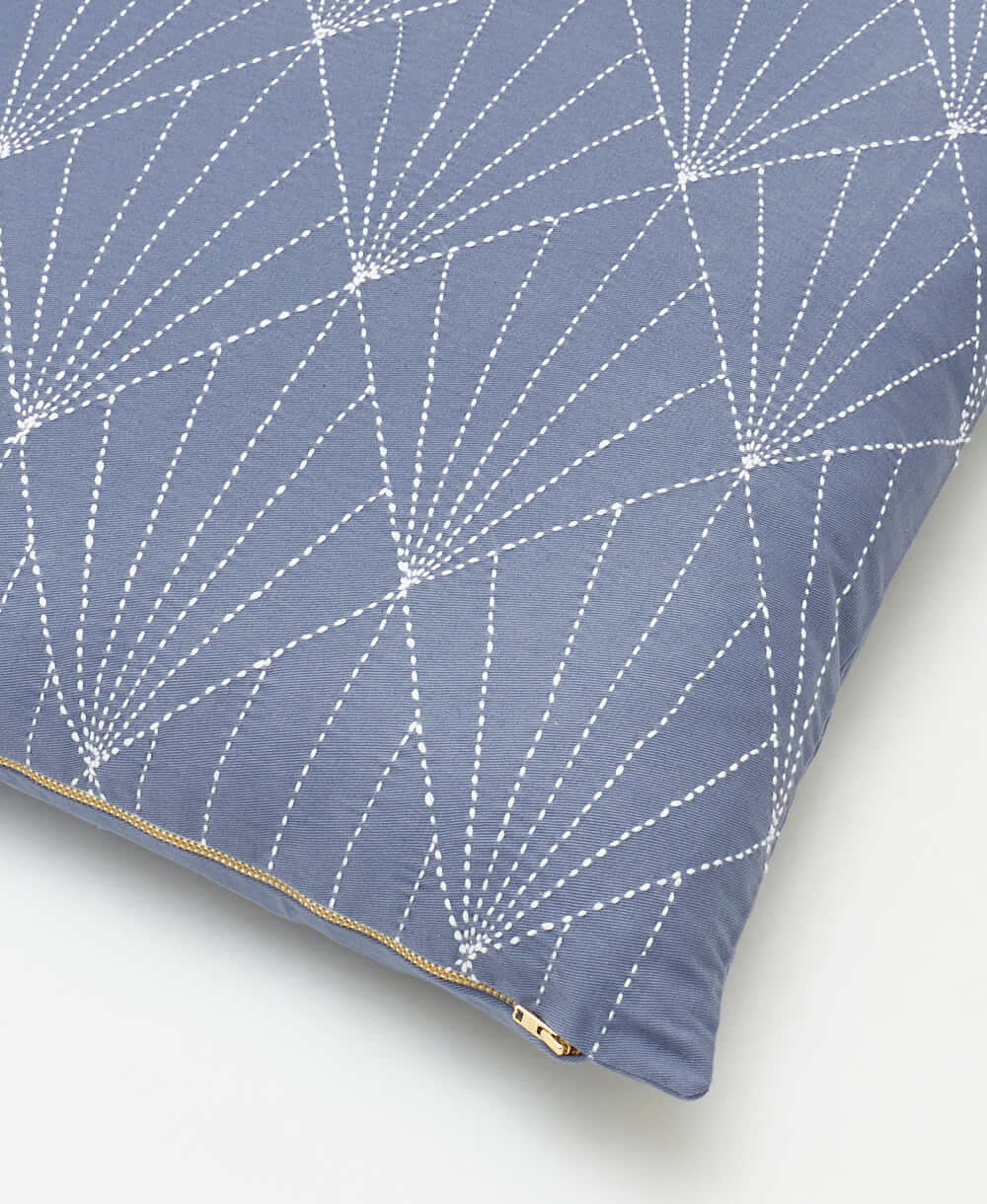 Blue pillow with white geometric pattern on a white background