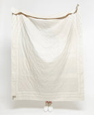 White quilt draped over a person on a white background