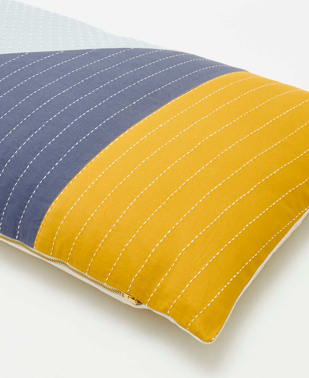 Two-toned blue and yellow pillow with visible stitching on a white background