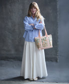 woman in blue and white striped poplin shirt holding mini canvas tote bag in baby pink & green floral