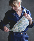 woman wearing crossbody sling bag in a blue floral block print pattern with zipper closure