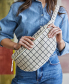 woman wearing grid print crossbody sling bag in black and white with adjustable strap to wear 2 ways
