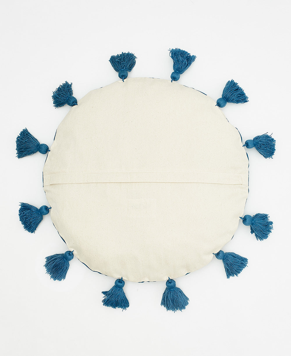 Round beige cushion with blue tassels on a white background