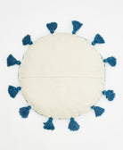 Round beige cushion with blue tassels on a white background