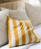 Yellow and white striped pillow on a beige sofa with other decorative pillows