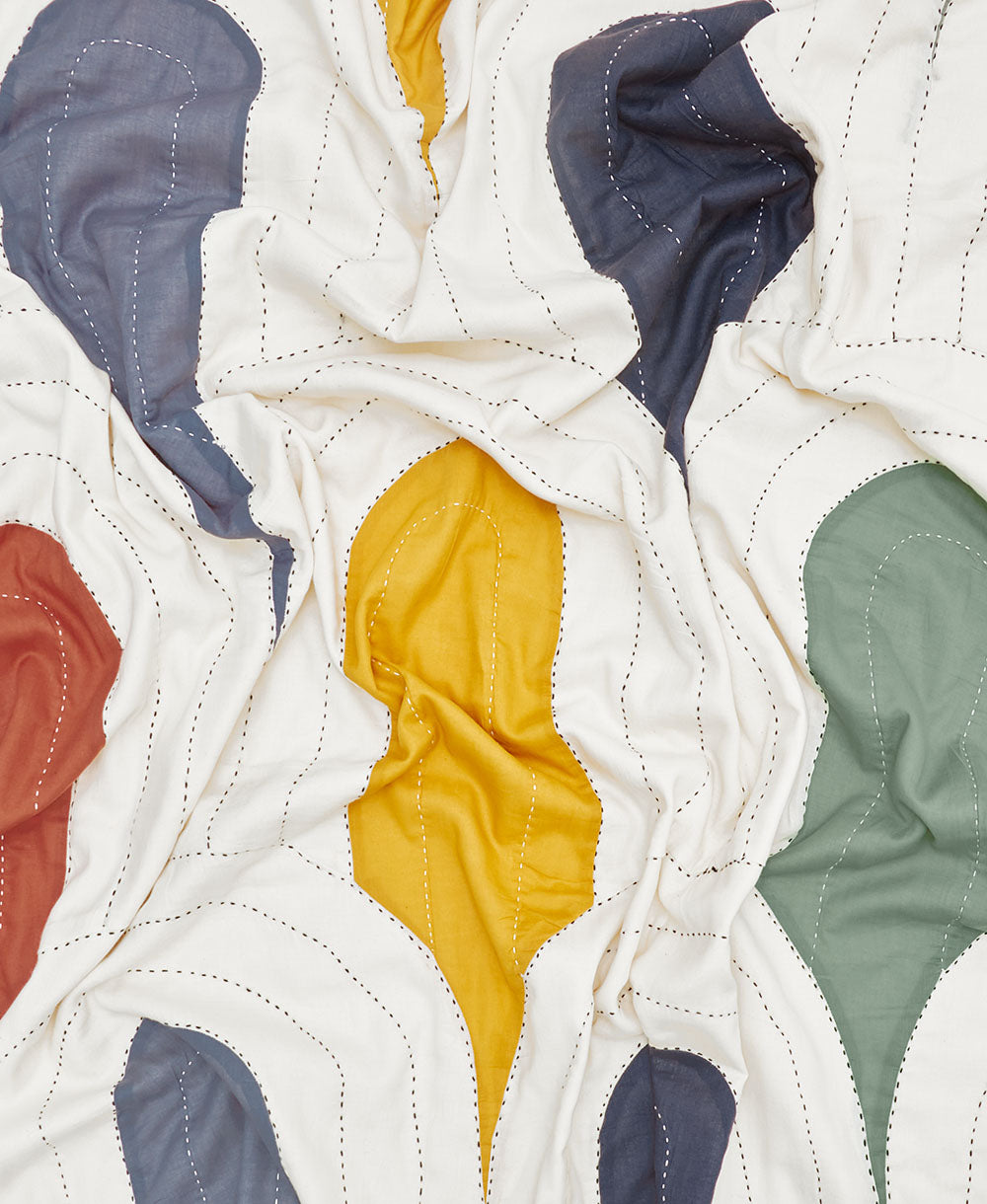 Close-up of a patchwork quilt with colorful fabric pieces on a white background