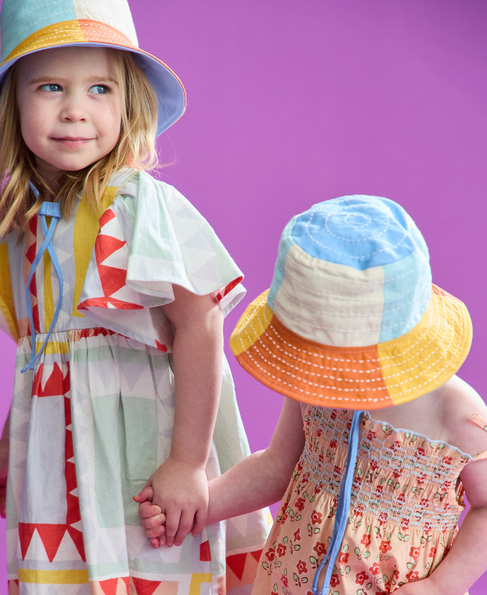 little girls holding hands and wearing colorful bucket hats