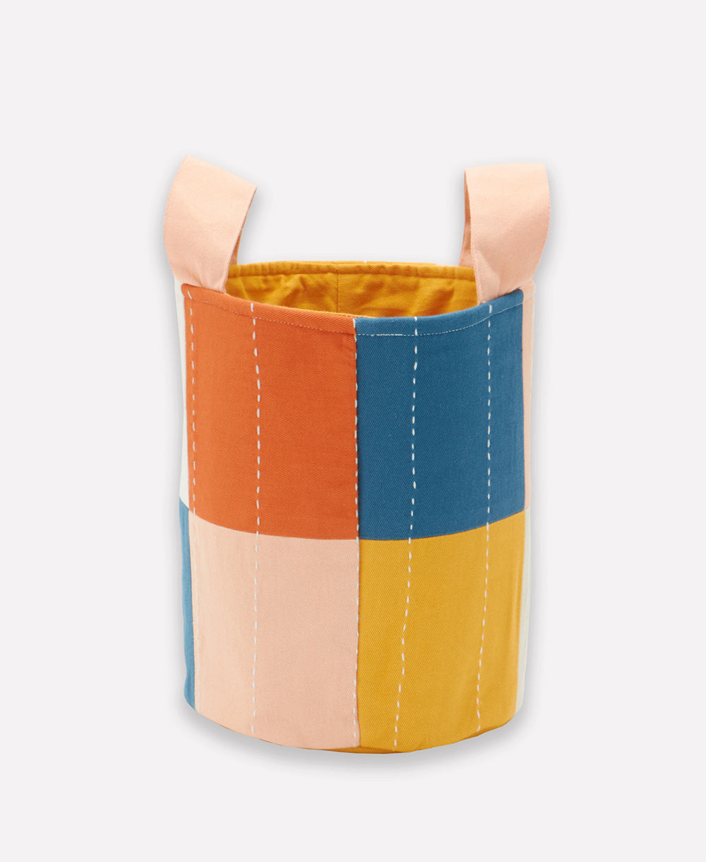 Colorful patchwork fabric basket with wooden handles on a white background