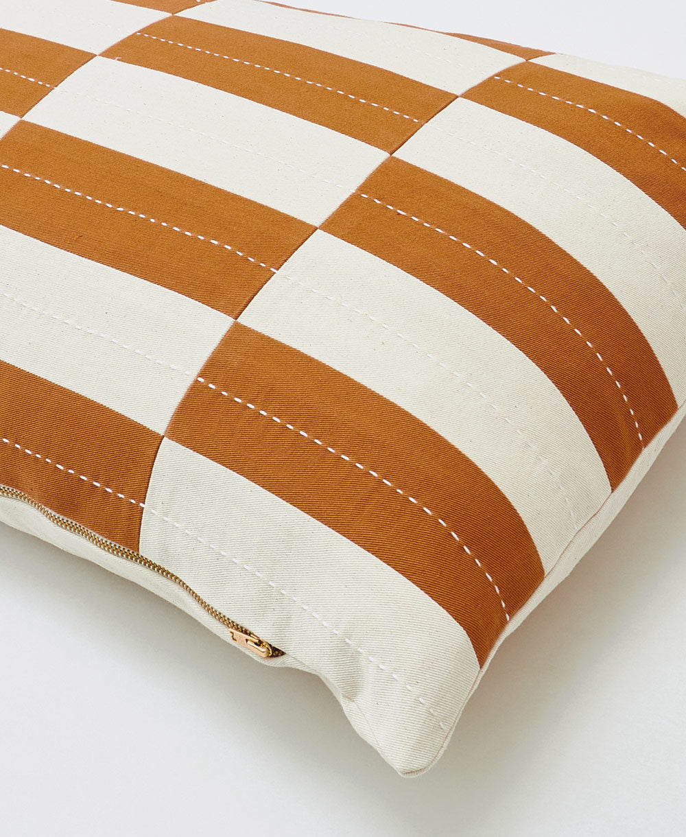 close-up of checkered lumbar pillow with brass tone zipper closure