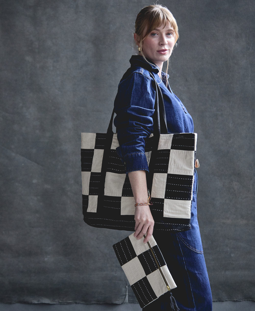 woman holding black and white checkered tote bag with matching pouch handmade in India from 100% organic cotton