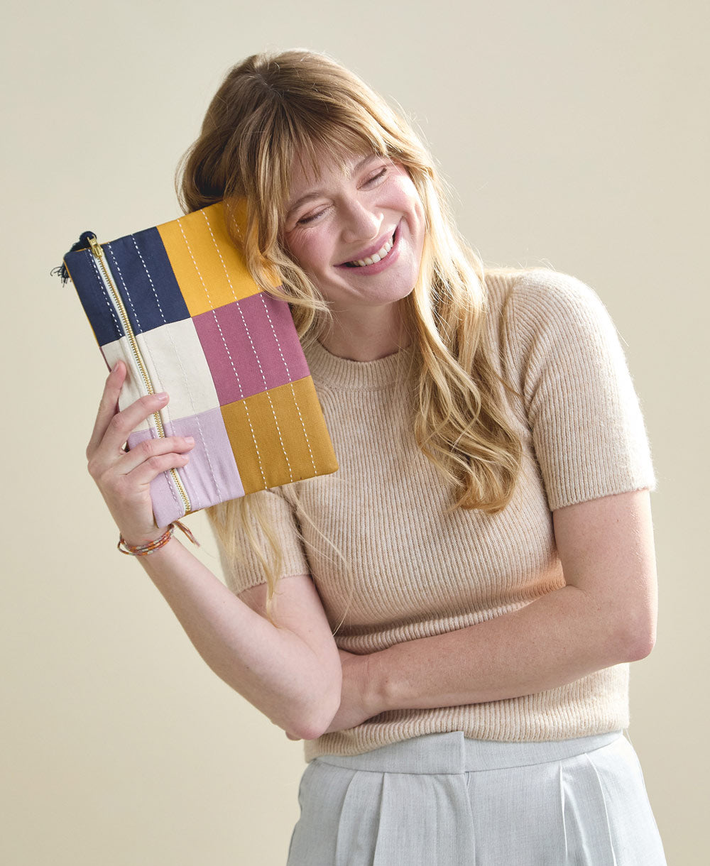 woman holding purple and navy checkered pouch with navy blue tassel