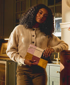 Woman holding a colorful patchwork bag in a kitchen setting