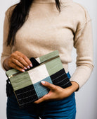 woman holding small sage green and navy blue pouch clutch handmade in India by women artisans