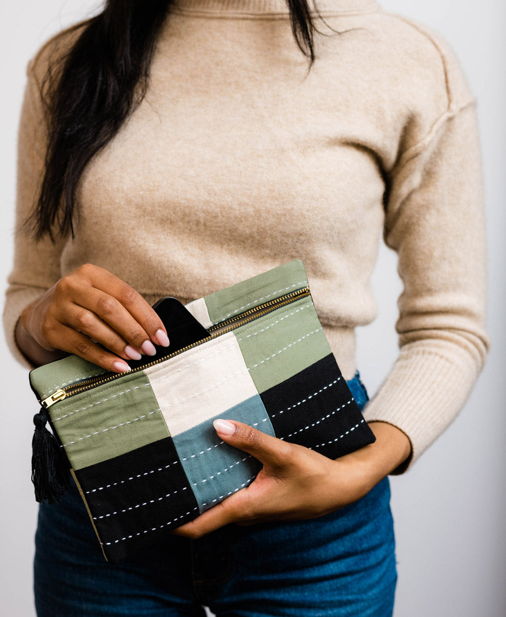 woman holding small sage green and navy blue pouch clutch handmade in India by women artisans