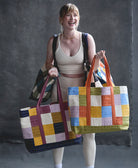 woman holding 5 checkered canvas tote bags in different colorways