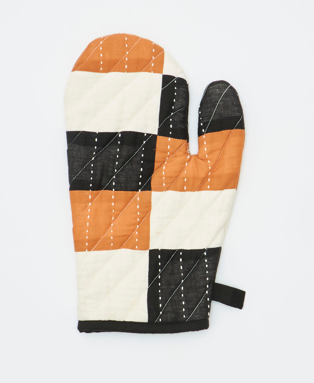 Patchwork oven mitt with black, brown, and white squares on a light gray background