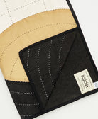 Close-up of a black and beige quilt with visible stitching and a brand label on a white background.
