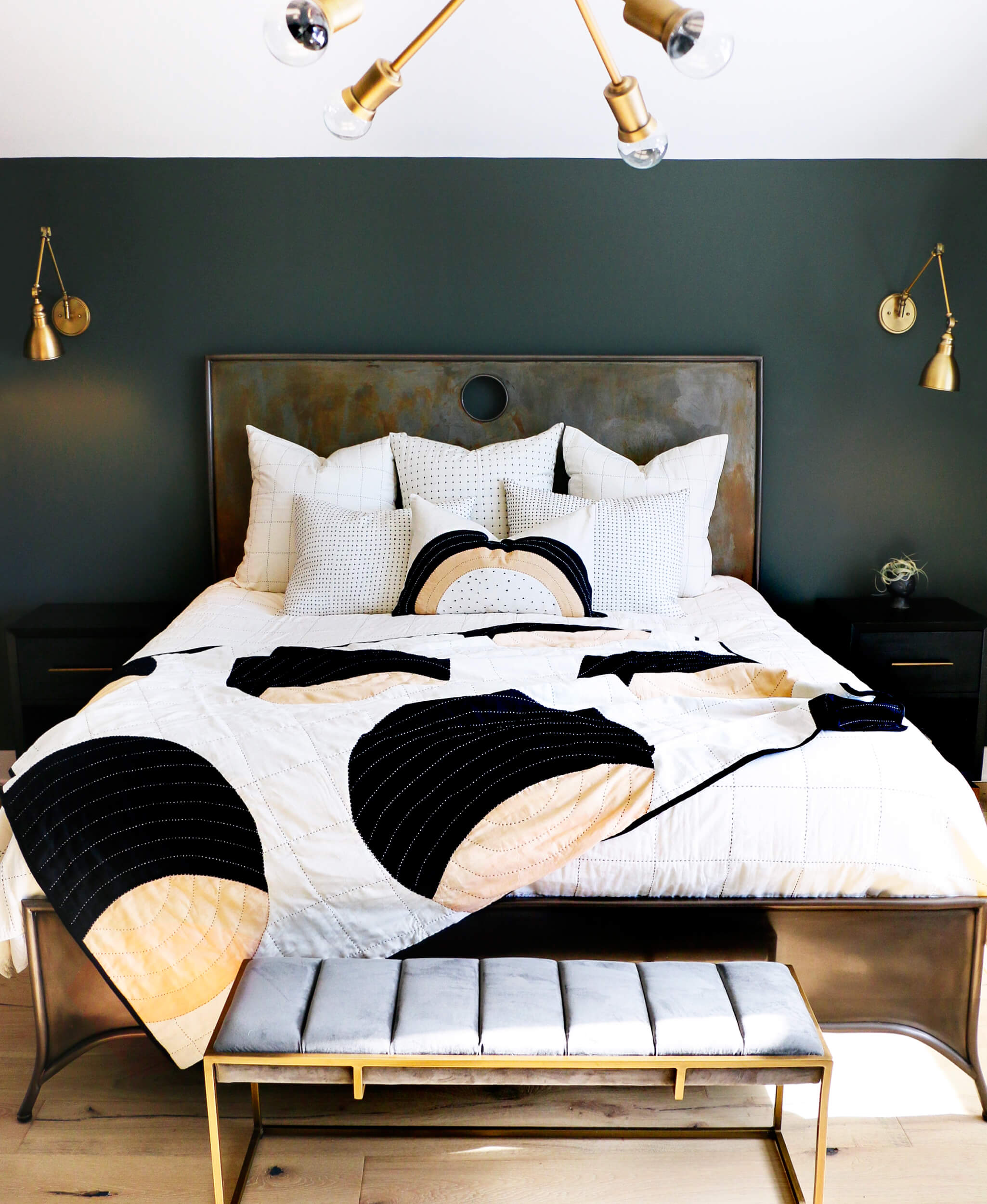 Modern bedroom with a bed featuring a black and white abstract patterned comforter, dark green walls, and gold accents.