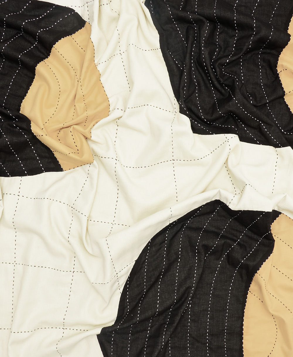 Close-up of a quilt with black, beige, and white pattern