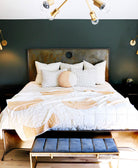 Neatly made bed with white bedding and decorative pillows in a bedroom setting