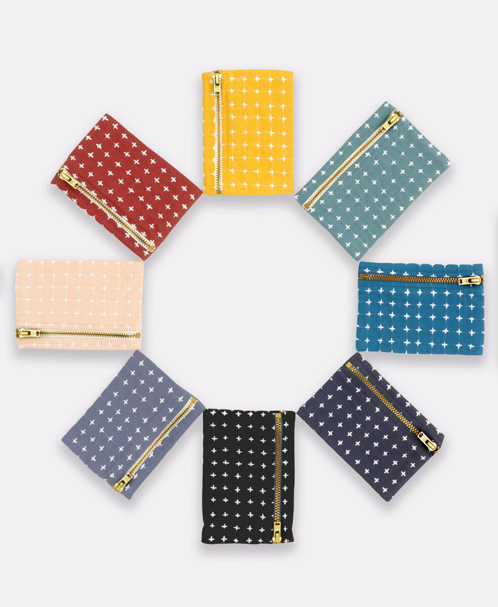 grouping of cross-stitch coin purses in a circle in a rainbow of colors