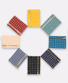grouping of cross-stitch coin purses in a circle in a rainbow of colors
