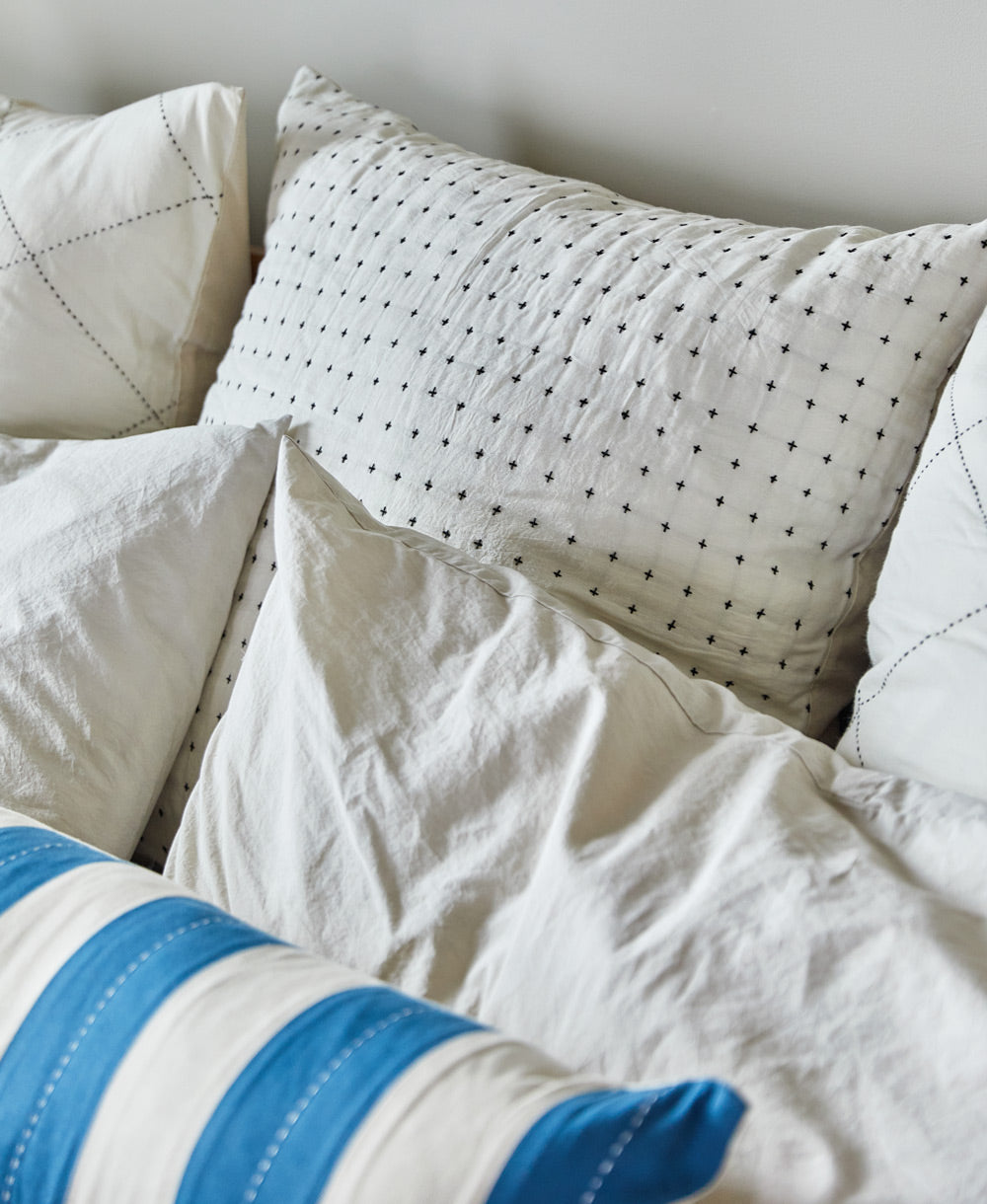 Close-up of textured pillows with different patterns and colors on a neutral background
