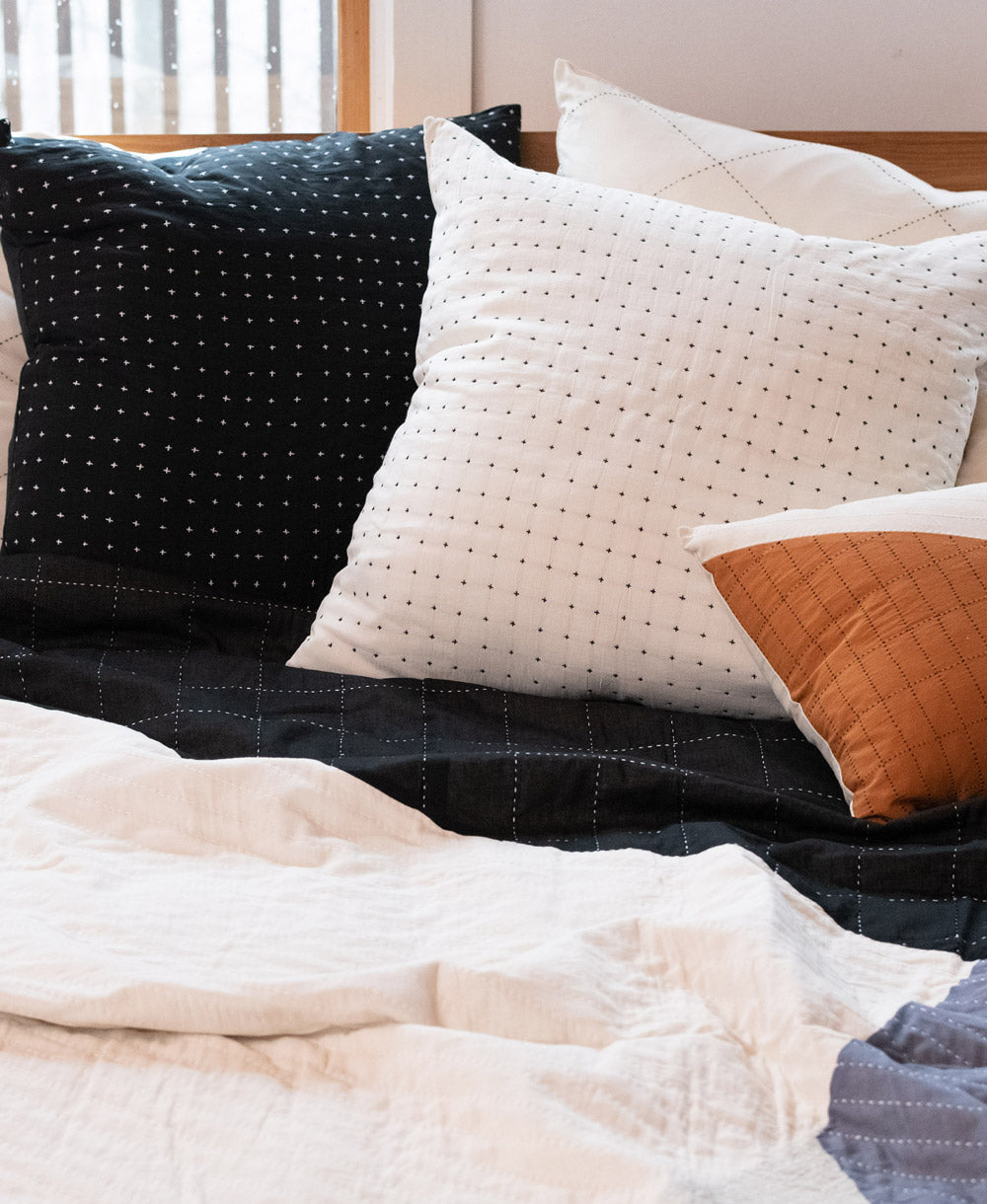 black and white cross-stitch euro shams on quilted bedding