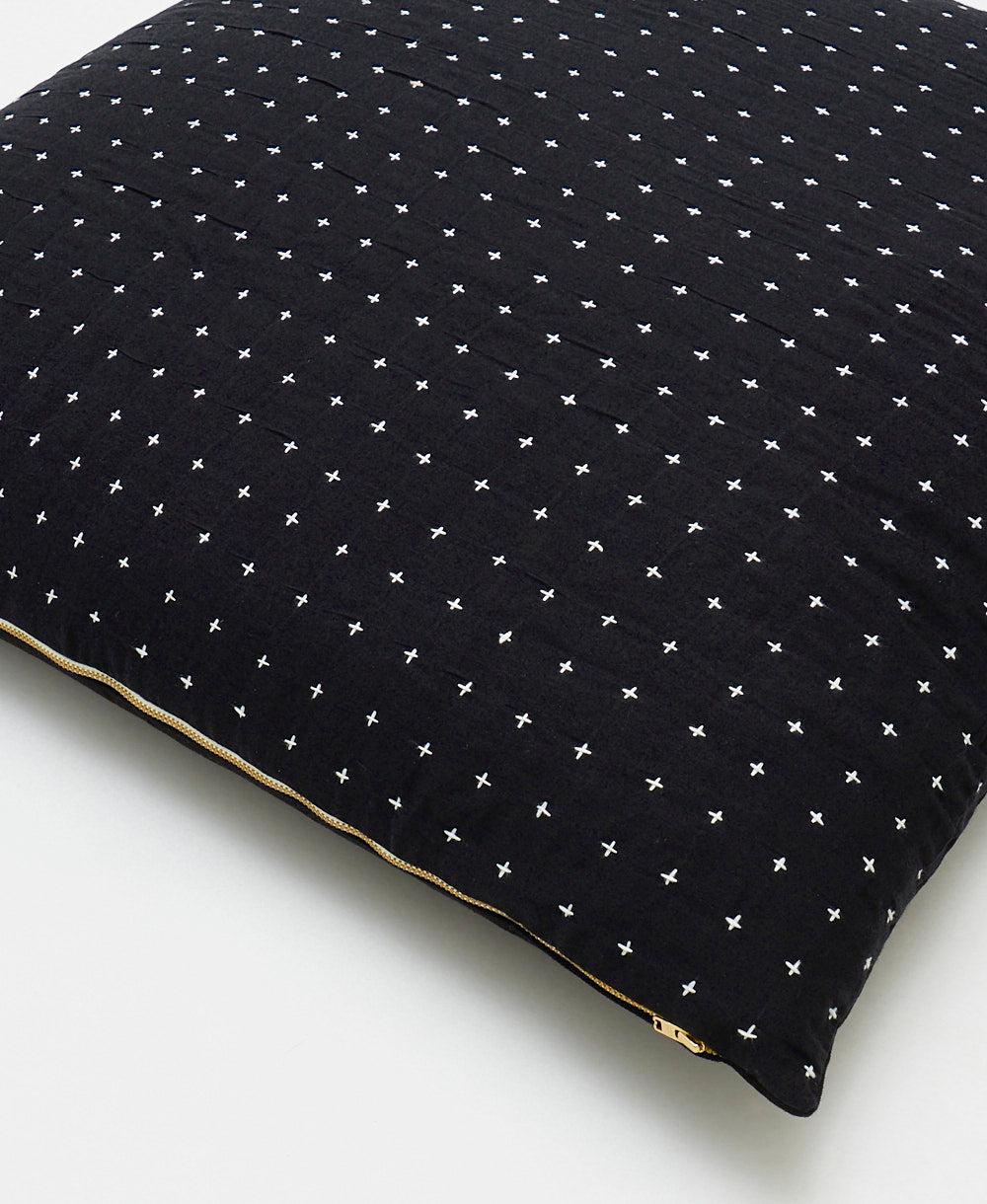 close up detail of black euro sham with white cross-stitch embroidery with brass zipper closure