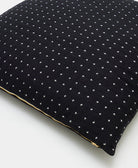 close up detail of black euro sham with white cross-stitch embroidery with brass zipper closure