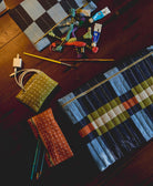 orange pencil case and green coin purse sitting on wooden desk with other checkered pouches