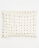 White pillow with black dot pattern on a white background