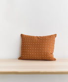 camel brown cross-stitch small pillow sitting on light wooden entryway bench